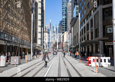 Sydney City Centre Büro Arbeiter auf der George Street im zentralen Geschäftsviertel zu Fuß über abgeschlossen Sydney Light Rail Tracks, Sydney, Australien Stockfoto