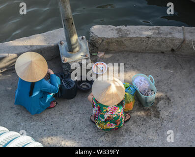 Frauen Anbieter sitzen auf der Straße in Saigon (Ho Chi Minh), Vietnam. Saigon ist die größte Stadt, und die ehemalige Hauptstadt der Republik Vietnam. Stockfoto