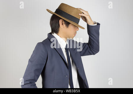 Jungen asiatischen Porträt Unternehmer im blauen Anzug Touch hat an der Seite Blick auf grauem Hintergrund Stockfoto