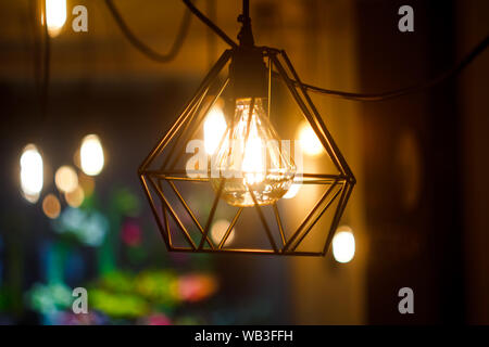 In der Nähe von glühenden sphärischen Retro Vintage Glühlampe Edison hängende Lampe in Metall Lampenschirm gegen den Hintergrund unscharf andere Lampen, selektive Schwerpunkte Stockfoto