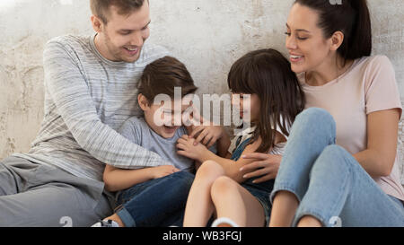 Lustige glückliche Eltern und kleine Kinder kitzeln auf dem Boden Stockfoto