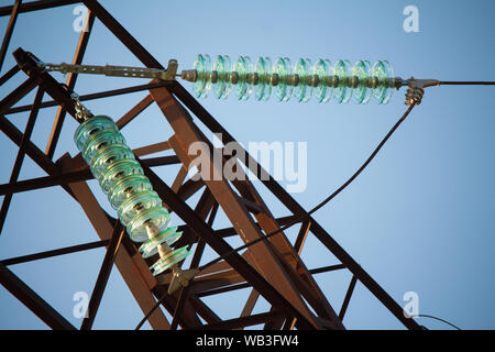 Nahaufnahme, Ansicht von unten von Isolatoren auf Hochspannungs-Leitungen auf einem Power Tower vor blauem Himmel Stockfoto