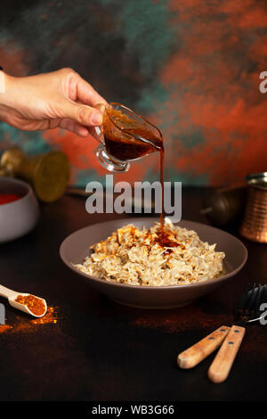 Traditionelle für türkische, griechische und iranische Küche, ein Gericht namens Keskek. Eingelegte Paprika, Butter und Paprikapulver. Die Soße auf den Teller gegossen Stockfoto