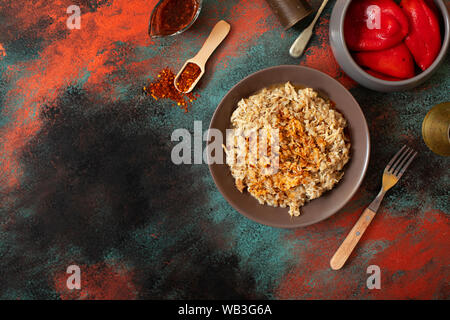 Traditionelle für türkische, griechische und iranische Küche, ein Gericht namens Keskek. Mit eingelegten roten Pfeffer, Butter und Paprikapulver serviert. Ansicht von oben Stockfoto