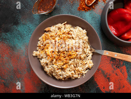 Traditionelle für türkische, griechische und iranische Küche, ein Gericht namens Keskek. Mit eingelegten roten Pfeffer, Butter und Paprikapulver serviert. Ansicht von oben Stockfoto