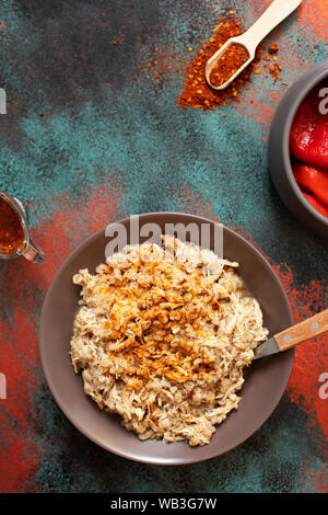 Traditionelle für türkische, griechische und iranische Küche, ein Gericht namens Keskek. Mit eingelegten roten Pfeffer, Butter und Paprikapulver serviert. Ansicht von oben Stockfoto