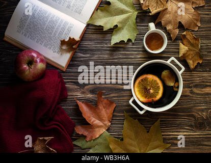 Warme Herbst und Winter alkoholisches Getränk Glühwein. Honig, Herbstblätter, Äpfel, ein Buch und einen wollpullover auf einer hölzernen Hintergrund. Herbst gemütliche Stimmung Stockfoto