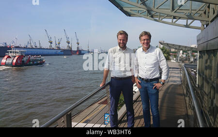 23. August 2019, Hamburg: Der Fraktionsvorsitzende von Bündnis 90/Die Grünen, Anjes Tjarks (l), und Dirk Kienscherf, Fraktionsvorsitzende der SPD, stehen an den Landungsbrücken. Sozialdemokraten und Grüne in Hamburg und Rotterdam wollen die Zusammenarbeit zwischen den beiden Hafenstädte bei der Verringerung der Luftverschmutzung durch Seeschiffe abgegeben zu fördern. Foto: Martin Fischer/dpa Stockfoto