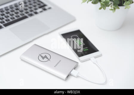 USB-Ladegerät angeschlossen zu Smart Phone. Power Bank, Handy Akku auf Schreibtisch Konzept Stockfoto