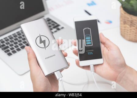 Mann Anschließen von USB-Ladegerät smart phone. Power Bank, Handy Akku auf Schreibtisch Konzept Stockfoto