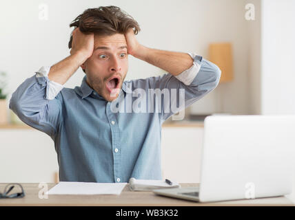 Enttäuscht Kerl auf Laptop, Hände auf den Kopf Stockfoto