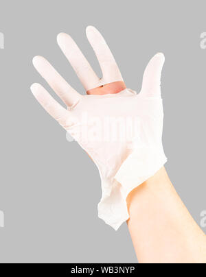 Gebrochen weißer latex Chirurg medizinische Handschuh auf kaukasische Hand isoliert auf graybackground. Stockfoto