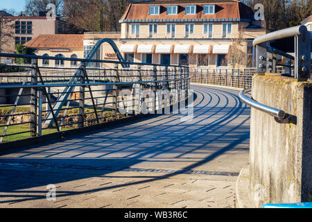 Bad Kissingen, Bayern, Deutschland - 16. Februar 2019: ein Frosch Perspektive einer modernen Brücke über der Fränkischen Saale mit Gebäuden in der Stockfoto