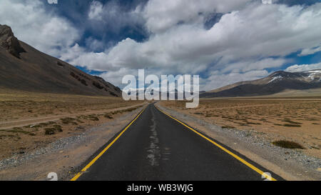 Straße in den Bergen des Himalayas und dramatische Wolken am blauen Himmel. Ladakh, Jammu und Kaschmir Stockfoto