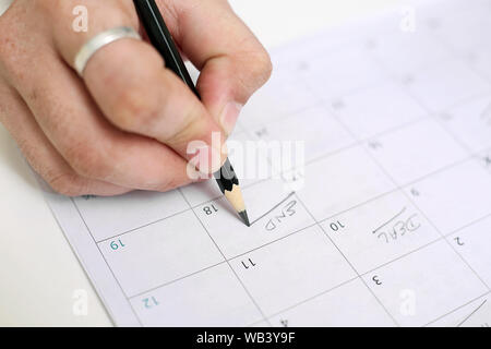 Bild von Mann mit Kalender und Kennzeichnung auf Datum. Auf weissem Hintergrund. Stockfoto