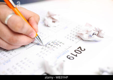 Bild von Mann mit Kalender und Kennzeichnung auf Datum. Auf weissem Hintergrund. Stockfoto