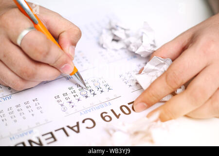 Bild von Mann mit Kalender und Kennzeichnung auf Datum. Auf weissem Hintergrund. Stockfoto