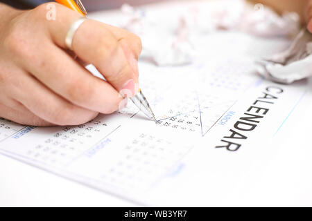 Bild von Mann mit Kalender und Kennzeichnung auf Datum. Auf weissem Hintergrund. Stockfoto