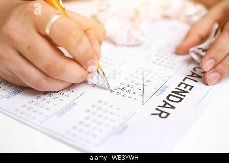 Bild von Mann mit Kalender und Kennzeichnung auf Datum. Auf weissem Hintergrund. Stockfoto