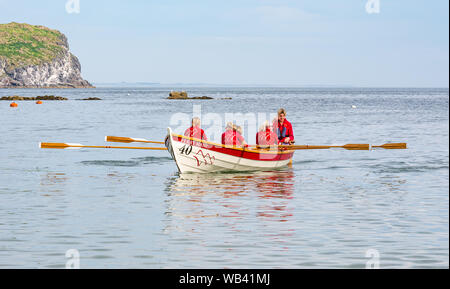 North Berwick, Schottland, Großbritannien, 24. August 2019. Farbenfrohe Ruderskiffe, die an der Regatta aus 12 Clubs in ganz Schottland teilnehmen, treten an einem heißen sonnigen Wochenende an, und rudern 2.5 km um Craigleith Island herum. Der St. Ayle's Skiff ist ein traditionelles Ruderboot mit 4 Ruderbooten. Im Bild: Der Queensferry Coastal Ruderclub und das Team Stockfoto