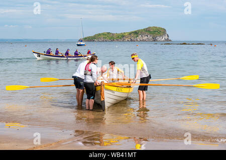 North Berwick, Schottland, Großbritannien, 24. August 2019. Farbenfrohe Ruderskiffe, die an der Regatta aus 12 Clubs in ganz Schottland teilnehmen, treten an einem heißen sonnigen Wochenende an, und rudern 2.5 km um Craigleith Island herum. Der St. Ayle's Skiff ist ein traditionelles Ruderboot mit 4 Ruderbooten. Boote und Teams des Coastal Ruderclubs Stockfoto