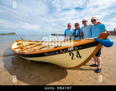 North Berwick, Schottland, Großbritannien, 24. August 2019. Farbenfrohe Ruderskiffe, die an der Regatta aus 12 Clubs in ganz Schottland teilnehmen, treten an einem heißen sonnigen Wochenende an den Feiertagen gegeneinander an. Der St. Ayles-Skiff ist ein traditionelles Ruderboot mit 4 Ruderbooten. Im Bild: Das Dunbar Coastal Ruderteam mit ihrem Skiiff Black Agnes Stockfoto