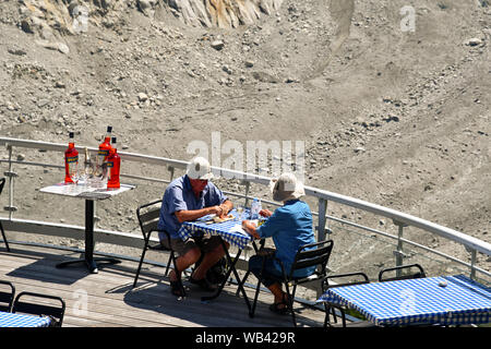 Ein älteres Ehepaar von Touristen sitzen in einem Café im Freien Restaurant von montenvers über den felsigen Gletscherspalte des Mer de Glace, Chamonix, Frankreich Stockfoto