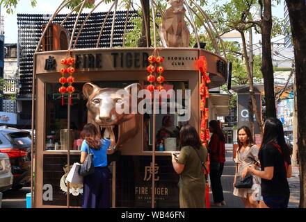 Eine Dame ist Sie ihr Getränk von Tiger Mund Feuer Tiger, das ist eine Erfrischung im Siam Square Shopping Center, Bangkok, Thailand Stockfoto