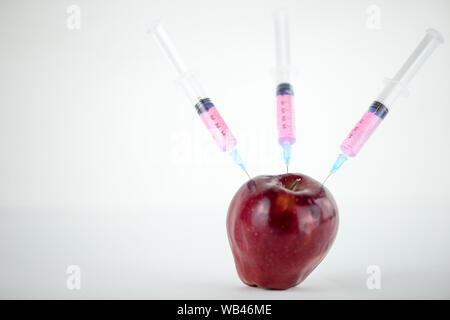 Konzept: die GVO-Manipulation der Natur und der relativen vergifteten Früchte. In der Nähe eines Apple verunreinigt mit drei Spritzen in Weiß und BA-Gewinde Stockfoto
