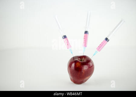 Konzept: die GVO-Manipulation der Natur und der relativen vergifteten Früchte. In der Nähe eines Apple verunreinigt mit drei Spritzen in Weiß und BA-Gewinde Stockfoto