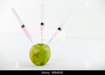 Konzept: die GVO-Manipulation der Natur und der relativen vergifteten Früchte. In der Nähe eines Apple verunreinigt mit drei Spritzen in Weiß und BA-Gewinde Stockfoto