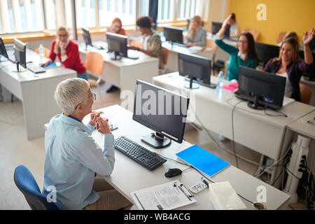 Lächelnd Lehrer etwas zu erklären, junge Studenten im Hörsaal Stockfoto