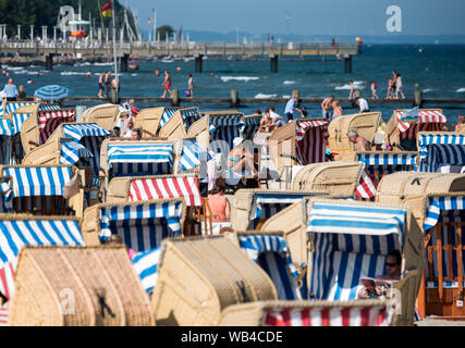 Lübeck-Travemünde, Deutschland. 24. August 2019, Schleswig-Holstein, Lübeck-Travemünde: Zahlreiche Menschen genießen das gute Wetter in Liegen am Strand der Ostsee. Foto: Daniel Bockwoldt/dpa Quelle: dpa Picture alliance/Alamy leben Nachrichten Stockfoto