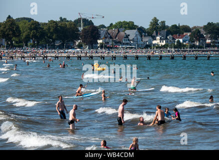 Lübeck-Travemünde, Deutschland. 24. August 2019, Schleswig-Holstein, Lübeck-Travemünde: Viele Menschen in der Ostsee schwimmen. Foto: Daniel Bockwoldt/dpa Quelle: dpa Picture alliance/Alamy leben Nachrichten Stockfoto