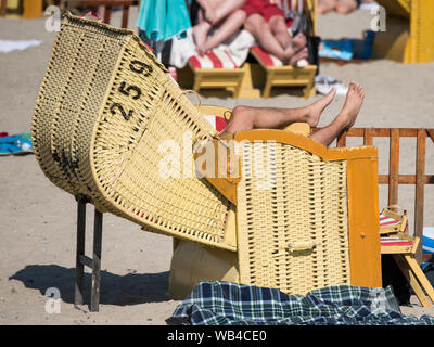 Lübeck-Travemünde, Deutschland. 24. August 2019, Schleswig-Holstein, Lübeck-Travemünde: ein Mann liegt am Strand an der Ostsee in einem Strandkorb. Foto: Daniel Bockwoldt/dpa Quelle: dpa Picture alliance/Alamy leben Nachrichten Stockfoto