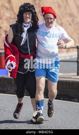 Sidmouth, 24 Aug 19 Läufern in den dreibeinigen Rennen während der Bank Holiday Sun in Honiton, Devon. Läufer auf 6 Pubs besuchen, und Trinken 0,33 in jedem während der Veranstaltung. Credit: Foto Central/Alamy leben Nachrichten Stockfoto