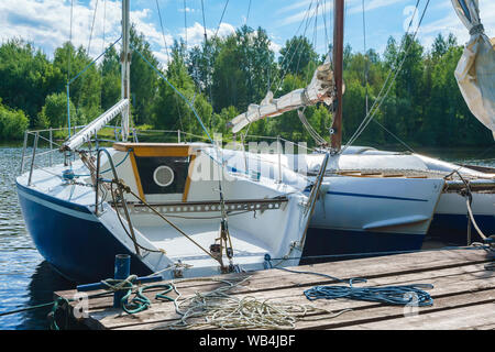 Zwei kleine Segelboote günstig an einer hölzernen Pier Stockfoto