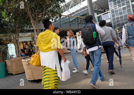 Frau trägt einen gelben Outfit zu Fuß einkaufen in Spitalfields Market Hall in East London England UK KATHY DEWITT Stockfoto