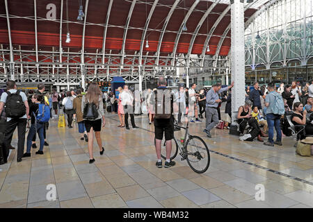 Passagiere Rückansicht Radfahrer Mann mit Fahrrad Rucksack innen warten auf der belebten Bahnhofshalle am Bahnhof Paddington in London England UK KATHY DEWITT Stockfoto