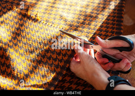 Junge Frau, die in einem nähen Studio: Schneiden von Gewebe mit einer Schere. Fashion Designer Atelier Stockfoto