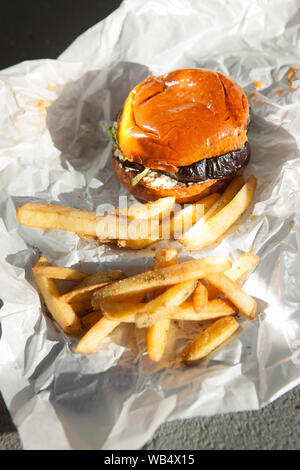 Köstlicher hausgemachter Gemüse-Burger mit Auberginen und Pommes auf weißem Papier. Vegetarische und vegane Speisen Stockfoto