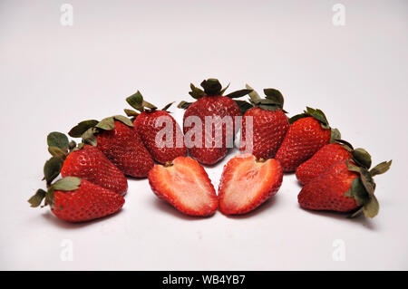Ganze und in Scheiben geschnittene Erdbeeren auf einer nahtlosen Hintergrund Stockfoto