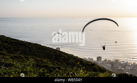 Gleitschirme Start von Cape Town Signal Hill bei Sonnenuntergang über dem Seapoint Vorort auf der Südafrikanischen Atlantik Stockfoto