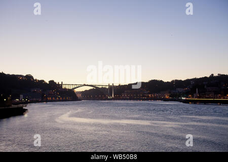 Der Fluss Douro (Rio Douro) in Porto und der Arrábida-Brücke (Ponte da Arrábida) im Licht der untergehenden Sonne - Portugal. Stockfoto