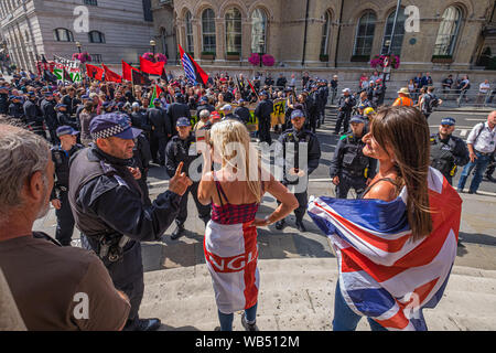 London, Großbritannien. 24. August 2019. Eine Frau an der Protest bei der BBC von Tommy Robinson Anhänger wird von der Polizei für beleidigende Sprache gewarnt. Die Demonstranten behaupten, er ist im Gefängnis für den Journalismus. Er wurde zu 9 Monaten für 3 Straftaten außerhalb von Leeds Crown Court, die den Zusammenbruch einer grooming Schleifring Versuch geführt haben könnte, verurteilt und hat Vorstrafen wegen Gewalt-, Finanz- und Einwanderung Betrügereien, Droge, Besitz und die öffentliche Ordnung Straftaten. Polizei die beiden Gruppen auseinander. Robinson Anhänger wurden später von Demonstranten vom Trafalgar Square, und mit einer größeren Gruppe aus dem Stand bis zu Rassismus kam Stockfoto