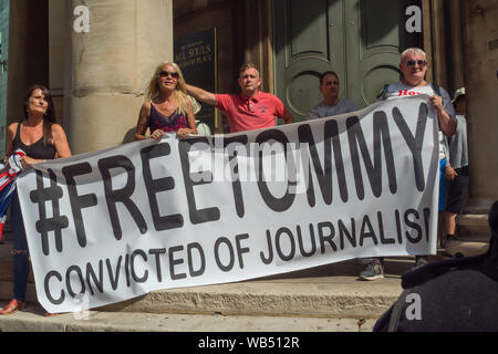 London, Großbritannien. 24 Aug, 2019. Tommy Robinson Unterstützer halten ein Banner '#FreeTommy überführt des Journalismus' auf die Schritte aller Seelen. Er wurde zu 9 Monaten für 3 Straftaten außerhalb von Leeds Crown Court, die den Zusammenbruch einer grooming Schleifring Versuch geführt haben könnte, verurteilt und hat Vorstrafen wegen Gewalt-, Finanz- und Einwanderung Betrügereien, Droge, Besitz und die öffentliche Ordnung Straftaten. Polizei die beiden Gruppen auseinander. Robinson Anhänger wurden später von Demonstranten vom Trafalgar Square, und mit einer größeren Gruppe aus dem Stand bis zu Rassismus kam Antifa zu verbinden. Credit: Peter Marschall/Alamy leben Nachrichten Stockfoto