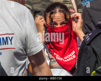 London, Großbritannien. 24. August 2019. Tommy Robinson Anhänger protestieren bei der BBC, darunter eine Frau mit einer roten Maske "Abstand halten". Sie behaupten, er ist im Gefängnis für Journalismus. Er wurde zu 9 Monaten für 3 Straftaten außerhalb von Leeds Crown Court, die den Zusammenbruch einer grooming Schleifring Versuch geführt haben könnte, verurteilt und hat Vorstrafen wegen Gewalt-, Finanz- und Einwanderung Betrügereien, Droge, Besitz und die öffentliche Ordnung Straftaten. Polizei die beiden Gruppen auseinander. Robinson Anhänger wurden später von Demonstranten vom Trafalgar Square, und mit einer größeren Gruppe aus dem Stand bis zu Rassismus kam Antifa zu verbinden. Pet Stockfoto