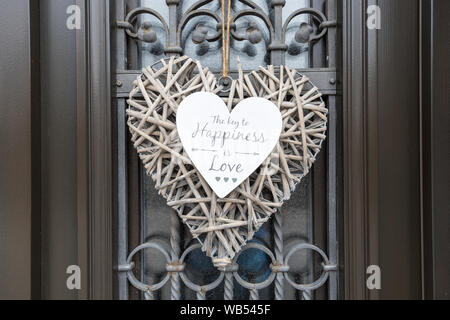 Ein wicker Herzen hängen an der Tür mit Glück und Liebe Zitat Stockfoto