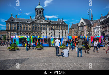 Amsterdam Dam Square mit dem Palais und die Straßenbahn während 70 Jahr Holland Festival 2017 ans Volk saß auf dem Platz Dam Stockfoto