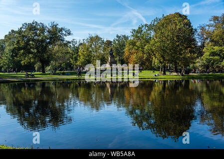 Reflexionen an Amsterdam Vondelpark im Herbst mit Bäumen in schönen Farben im Wasser spiegeln und einer Statue von Joost van den Vondel Stockfoto